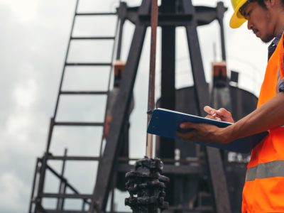 Workers standing and checking beside working oil pumps.